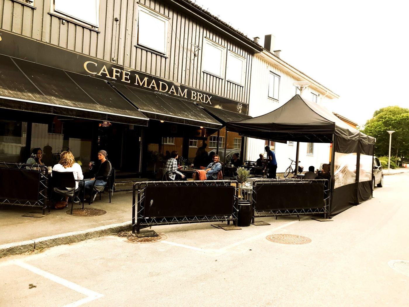 Fasaden til Cafe Madam Brix med uteservering og telt i gata