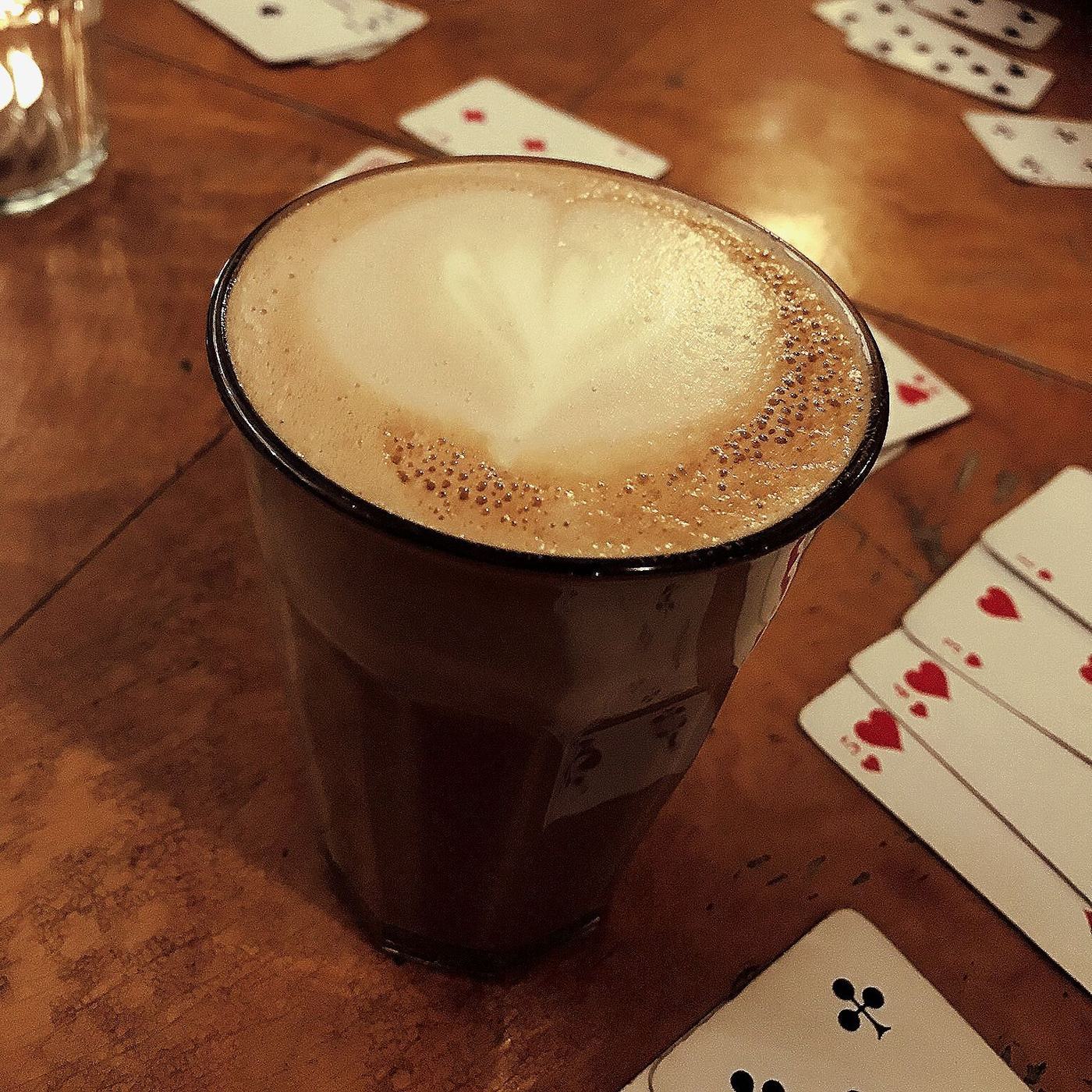 Kaffe latte i glass på et trebord med spillkort rundt