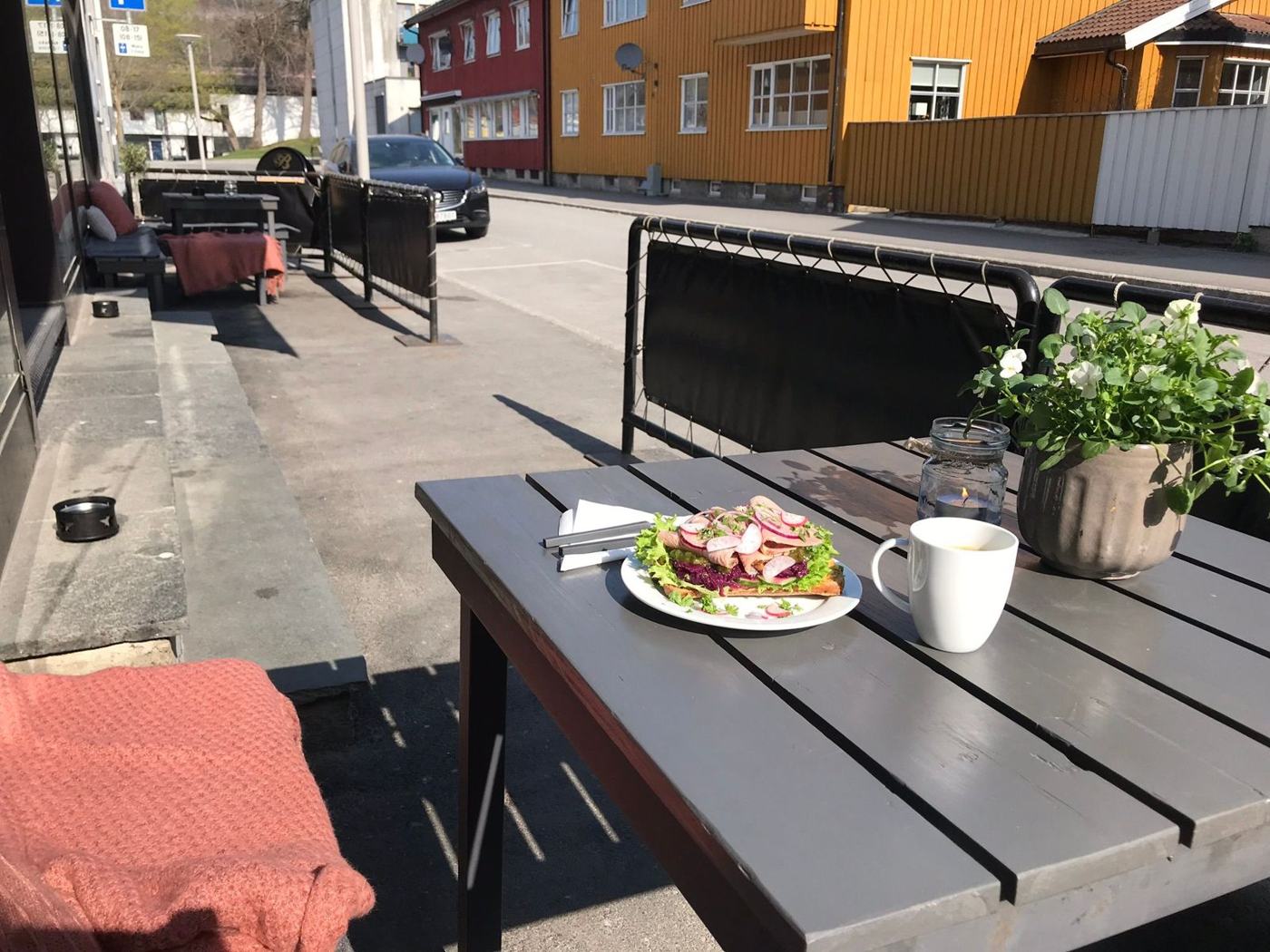 Påsmurt og en kopp kaffe på et bord ute i sola